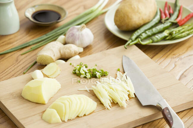 Gehackte Kartoffeln und andere Zutaten mit Messer auf Schneidebrett — Stockfoto