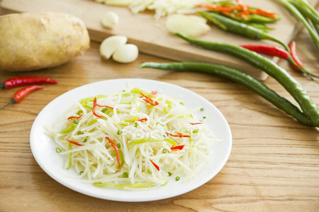 Shredded potato with chili pepper slices served on plate — Stock Photo