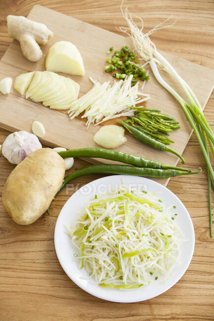 Измельченный картофельный салат с нарезанными ингредиентами на деревянной доске — стоковое фото