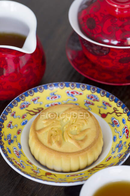 Moon cake on ornate plate and tea in jug and cup — Stock Photo