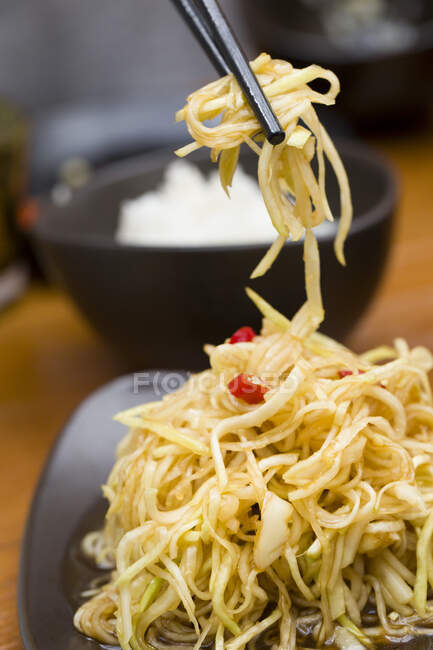 Cucina cinese, insalata di ravanello triturata sul piatto e in bacchette — Foto stock