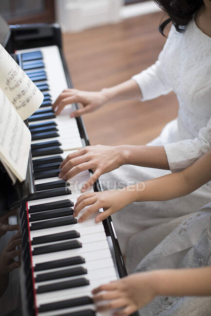 Plan recadré de mère et fille jouant du piano — Photo de stock