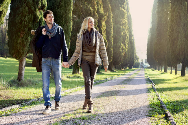 Пара, гуляющая по листовой аллее в осенний день — стоковое фото