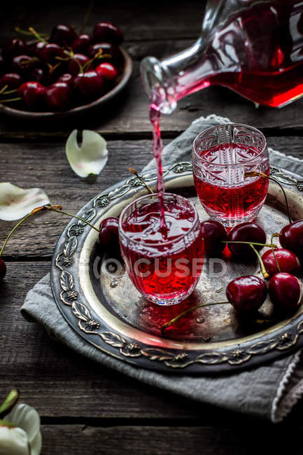 Licor casero de cereza fluyendo en un vaso vintage . - foto de stock