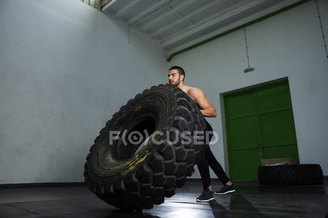 Bodybuilder kippt Reifen im Fitnessstudio — Stockfoto