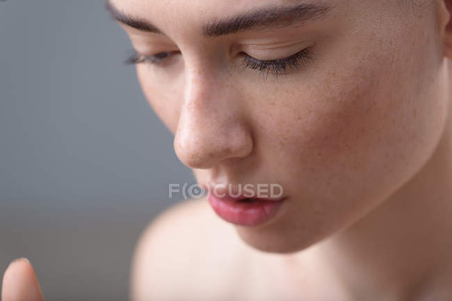 Visage de fille avec taches de rousseur sur fond gris et espace de copie — Photo de stock