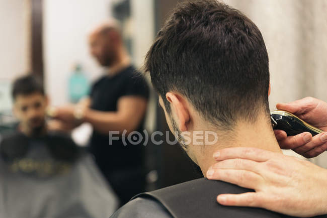 Parrucchiere rendendo taglio di capelli degli uomini ad un uomo attraente . — Foto stock