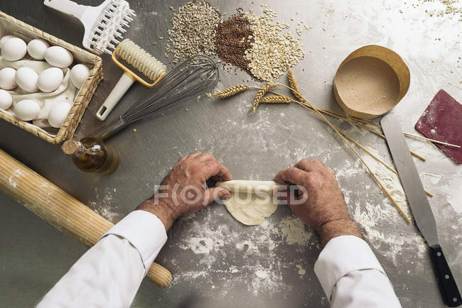 Baker amassar a massa de farinha em uma padaria. — Fotografia de Stock