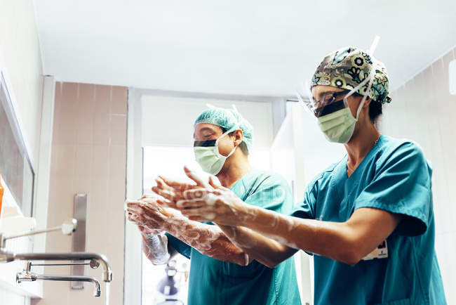 Pareja de cirujanos lavándose las manos antes de operar . - foto de stock
