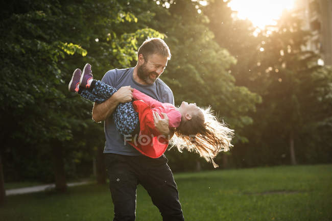 Dedicado pai girando sua filha em círculos — Fotografia de Stock