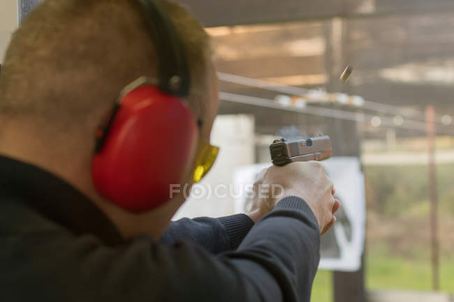 A disparar com uma pistola. Homem disparando pistola na faixa de tiro . — Fotografia de Stock