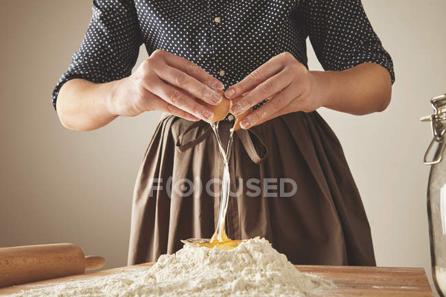 Femme casse oeuf au-dessus de la farine — Photo de stock