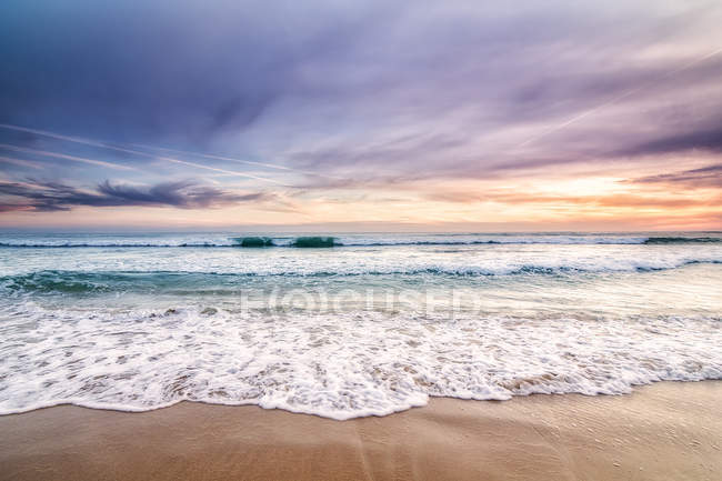 Ondas e areia ao pôr do sol na praia — Fotografia de Stock