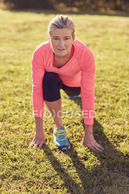 Active senior woman stretching on grass — Stock Photo