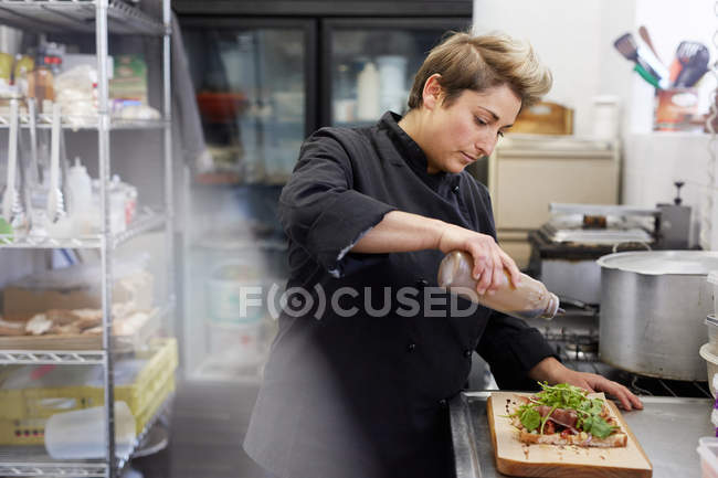 Koch träufelt Balsamico-Essig auf Sandwich — Stockfoto