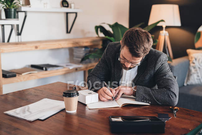 Unternehmer schreibt in Notizbuch mit Lieferbox — Stockfoto