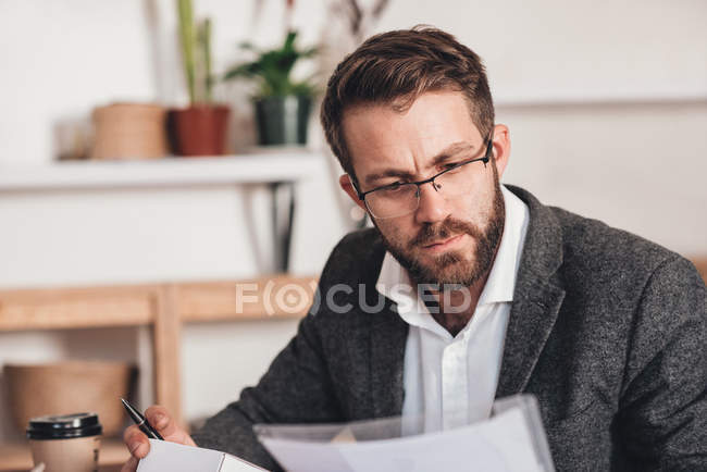 Unternehmer liest Papierkram und bereitet Pakete vor — Stockfoto