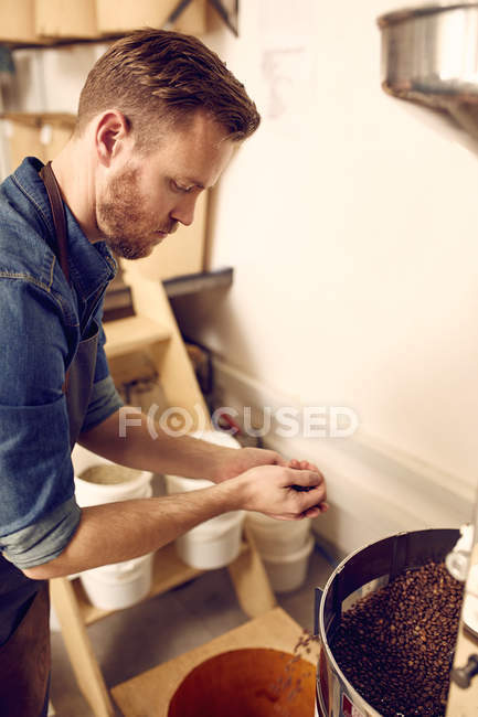 Mann schüttet Kaffeebohnen in Maschine — Stockfoto