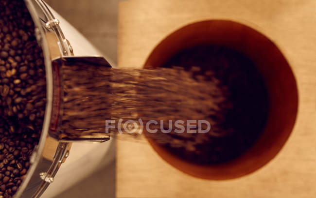 Chicchi di caffè tostati che cadono in contenitore — Foto stock