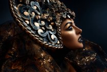 Portrait de femme avec un maquillage fantaisie portant une grande couronne — Photo de stock