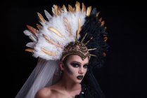 Frau mit modischem Make-up trägt Federkrone — Stockfoto