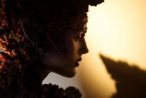 Perfil jovem mulher com fantasia maquiagem arte e decorações florais em backlit — Fotografia de Stock