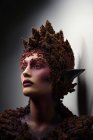 Junge Frau mit Fantasie-Make-up und floralem Dekor, die wegschaut — Stockfoto