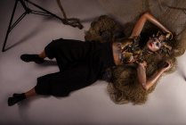 Женщина-монстр с головным убором и одеждой из рыб, лежащих на земле с сеткой — стоковое фото