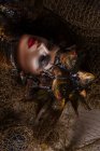 Nahaufnahme Porträt eines weiblichen Monsters mit Kopfschmuck und Kleidung aus Fischen, die mit Netz posieren — Stockfoto