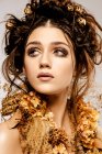Attractive fashionable woman with golden makeup and wreath looking away — Stock Photo