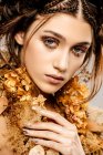 Attractive fashionable woman with golden makeup and wreath looking at camera — Stock Photo