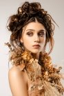 Attrayant femme à la mode avec maquillage doré et couronne regardant loin — Photo de stock