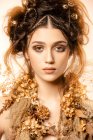 Привлекательная модная женщина с золотым макияжем и венком, смотрящая в камеру — стоковое фото