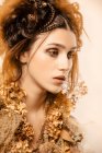 Mulher elegante atraente com maquiagem dourada e coroa olhando para longe — Fotografia de Stock