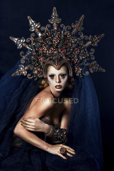 Woman with fantasy makeup wearing large crown and posing at camera — Stock Photo