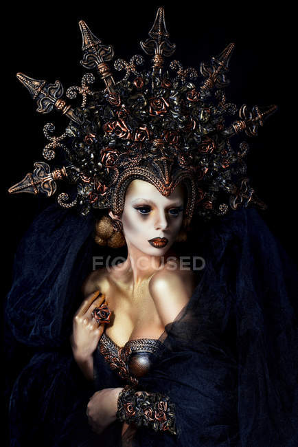 Woman with fantasy makeup wearing large crown and posing at camera — Stock Photo