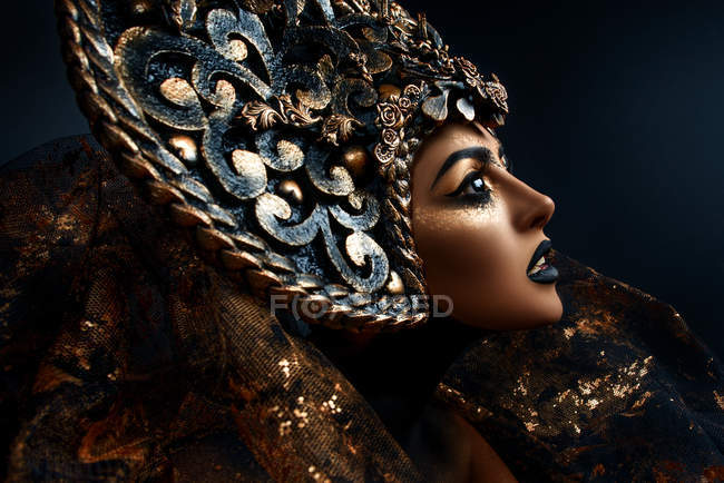 Portrait of woman with fantasy makeup wearing large crown — Stock Photo