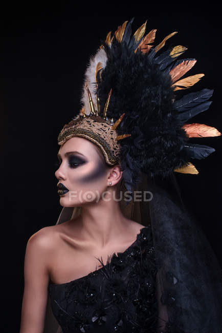 Frau mit modischem Make-up trägt Federkrone — Stockfoto
