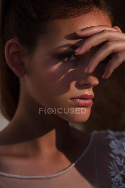 Femme attrayante couvrant le visage et regardant la caméra par les doigts — Photo de stock