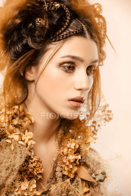 Attraente donna alla moda con trucco dorato e ghirlanda guardando altrove — Foto stock