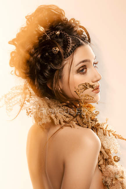 Vue latérale de la femme à la mode attrayante avec le maquillage doré et la couronne regardant loin — Photo de stock