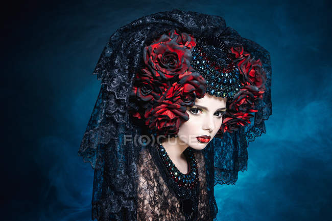 Fashionable shoot of woman with veil and red flowers — Stock Photo