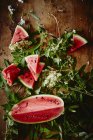 Frische in Scheiben geschnittene Wassermelone und grüne Blätter — Stockfoto
