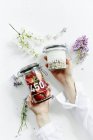 Hände halten Getreide und Erdbeeren in Gläsern — Stockfoto