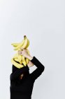 Donna nascondendo faccia sotto banane — Foto stock