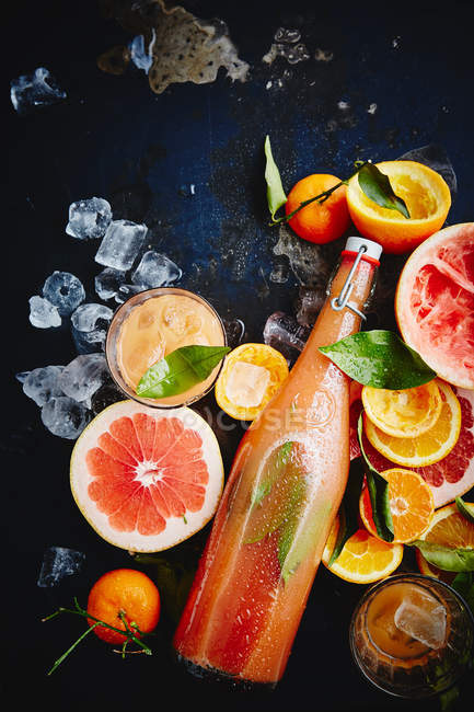 Sumo de citrinos em garrafa de vidro e frutas — Fotografia de Stock