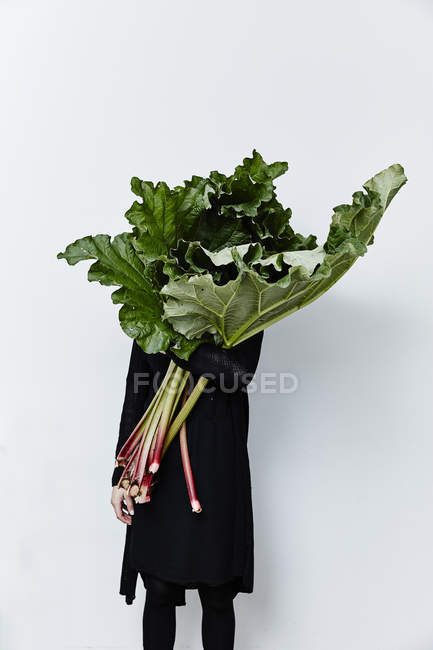 Mujer escondida detrás de hojas de ruibarbo - foto de stock