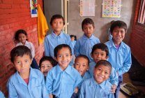 Niños en uniforme escolar sonriendo a la cámara - foto de stock