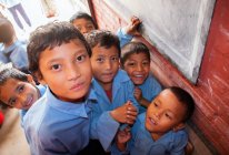 Niños en uniforme escolar sonriendo a la cámara - foto de stock