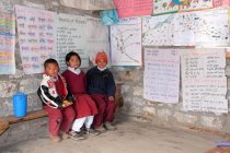 Meninos e meninas de uniforme sentados em sala de aula — Fotografia de Stock